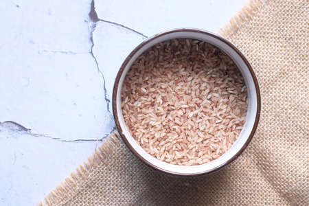 raw brown rice on wooden background top down.の写真素材