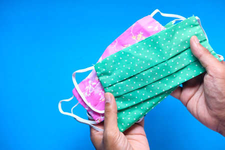 man hand holding homemade protective mask on blue background