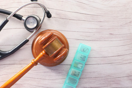 Top view of gavel, stethoscope and pills on wooden background