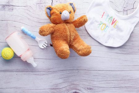 Toys for newborn baby set with teddy bear and milk in bottle on wooden table