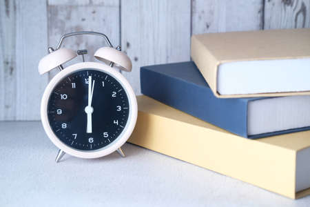 stack of books and clock on table close upの写真素材