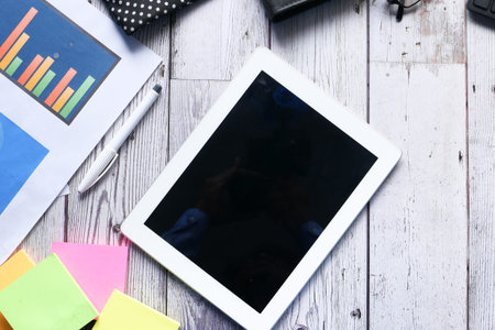 Flat composition of digital tablet and office stationary on wooden background