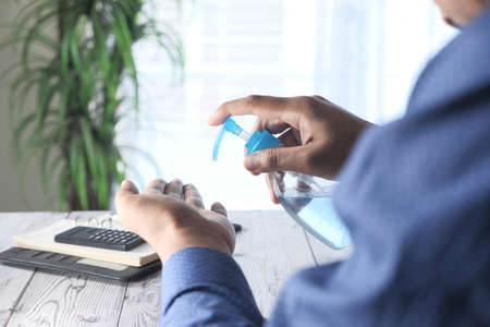 back view of businessman using sanitizer gel on on office deskの写真素材