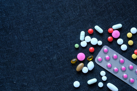 close up of colorful pills spilling on black background