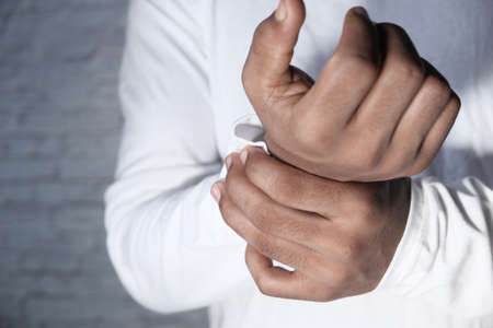 Young man in white shirt suffering wrist pain, close upの写真素材