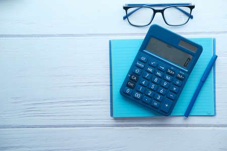 Close up of blue calculator and notepad on color backgroundの写真素材
