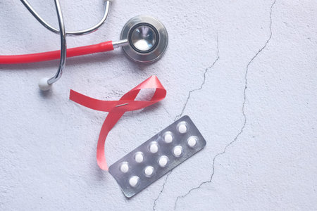 Red ribbon HIV, and stethoscope on white background.