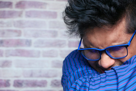 Young ill man covering her nose and mouth with arm.