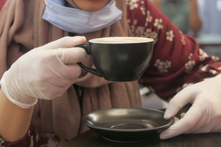 women in medical gloves drinking coffee at cafe.