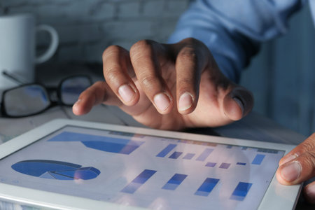 young man hand analyzing financial data and chart on digital tablet