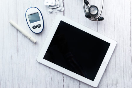 top view of digital tablet, pills and diabetic measurement tool on table