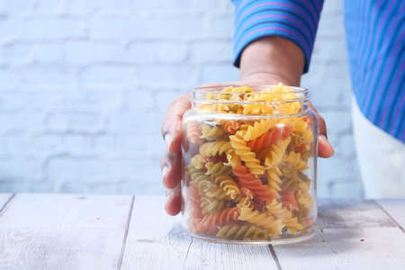 Man hand holding a jar of dry Italian pastaの写真素材