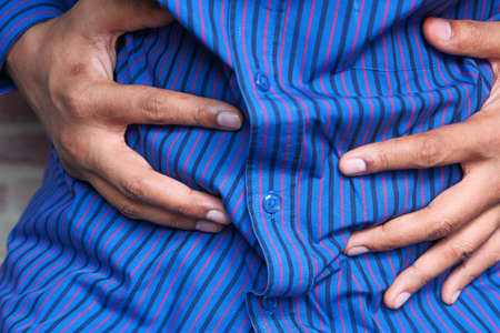 young man suffering stomach pain close up.の写真素材