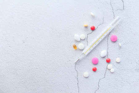 medical thermometer and pills on white texture backgroundの写真素材