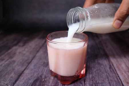 Close up of pouring milk into the glass on wood table