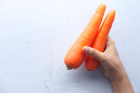 top view of women hand holding carrot on white background.の写真素材