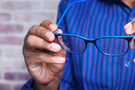 Close up of man hand holding eyeglass in dark.