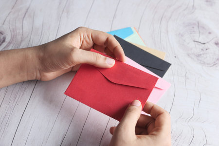 Love letter in women hand on red background , Top view.