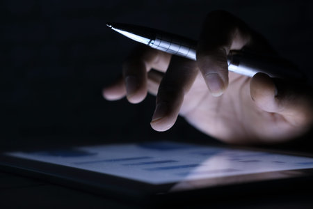 mans hand working on digital tablet at office desk, using self created chart