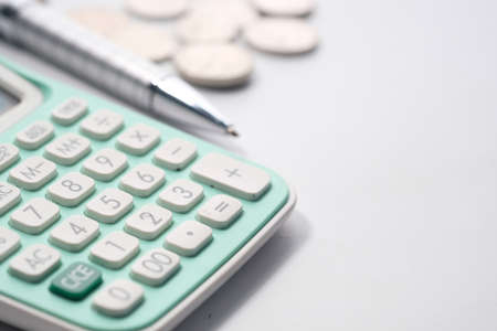 Close up of calculator, pen and coins on white backgroundの写真素材