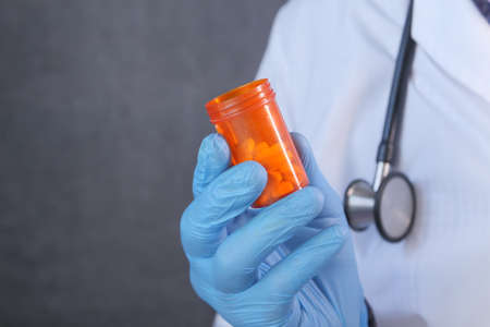 doctor hand in protective glass holding pill containerの写真素材