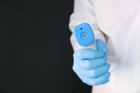 Hand holding infrared thermometer to measuring temperatureの写真素材
