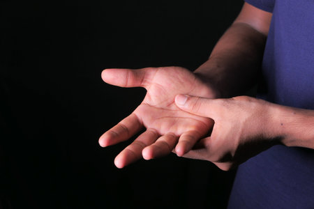 man with hand pain isolated in black.