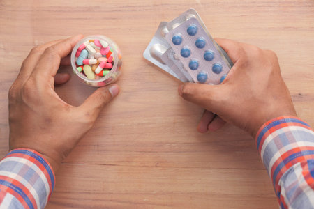 top view of man holding pill container and blister pack
