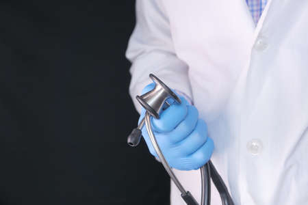 doctor hand in protective gloves holding stethoscopeの写真素材