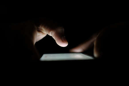 Close up of hacker hand stealing data from smart phoneの写真素材