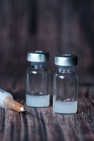 Close up of coronavirus vaccine and syringe on black backgroundの写真素材