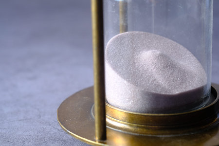 hourglass on table, sand flowing through the bulb of sandglass