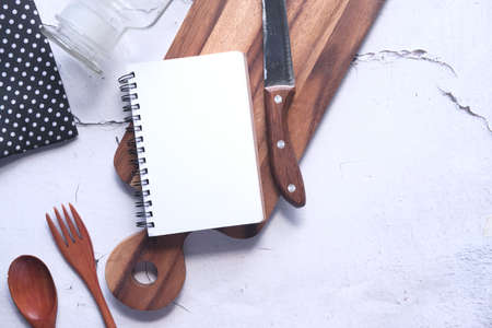 Notepad on chopping board with spoon on tableの写真素材