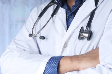 Doctor in hand gloves holding stethoscope indoor.