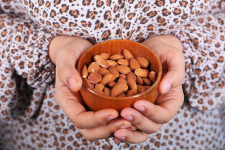 close up women hand holding a bowl on almond