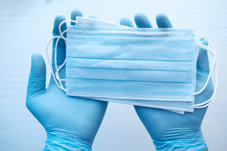 man hand in protective gloves holding surgical face mask,