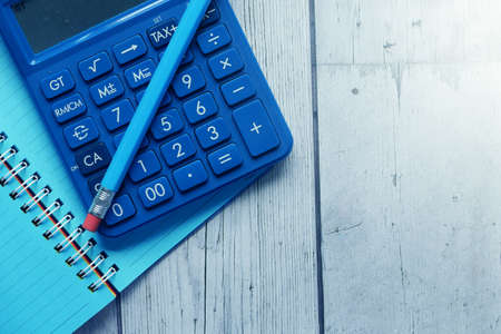 Close up of blue calculator and notepad on color backgroundの写真素材