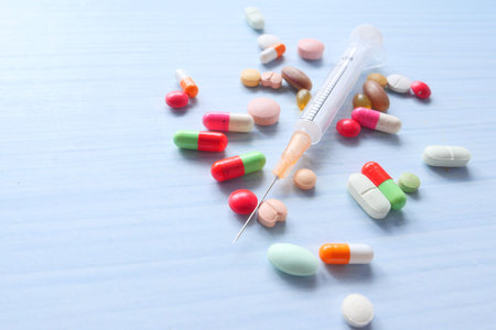 syringe and pills on wooden background, close up