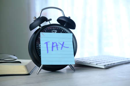 Tax word on alarm clock with stationary on table.の写真素材