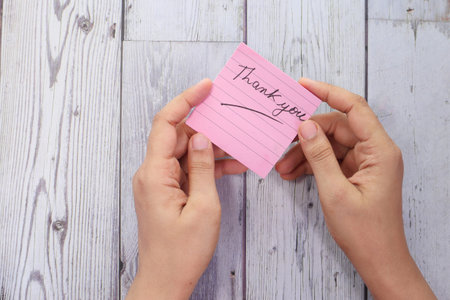 womens hand holding thank you note , top down