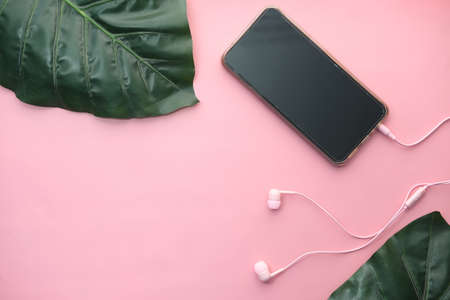 smart phone with empty screen, earphone on pink backgroundの写真素材