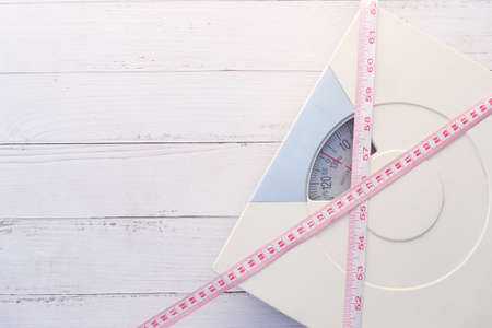 a tape measure and Bathroom scale on wooden floor.の写真素材