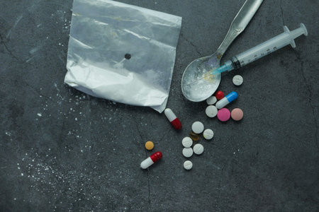 drug addiction concept with heroine packet and syringe on black backgrund
