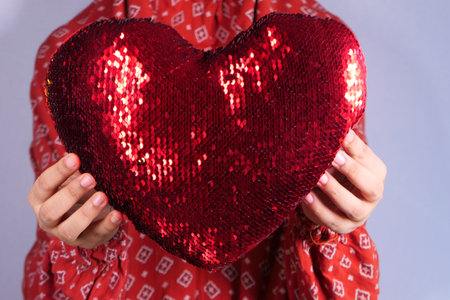 women holding red heart in hands