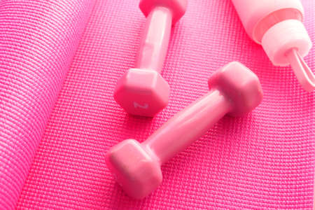 Close up of dumbbell and water bottle on pink color exercise matの写真素材