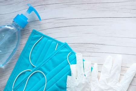 Surgical masks and hand sanitizer on green background