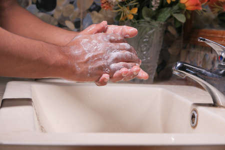 young man washing hands with soap warm waterの写真素材