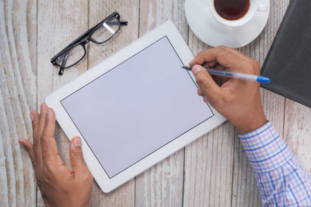 top view of mans hand working on digital tablet at office desk