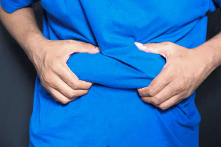 mans hand holding excessive belly fat, overweight conceptの写真素材