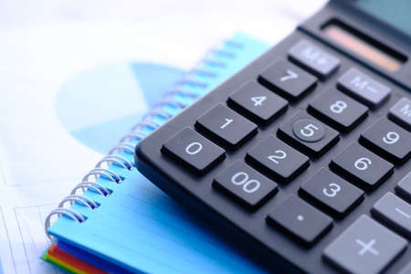 Close up of blue calculator and notepad on color backgroundの写真素材